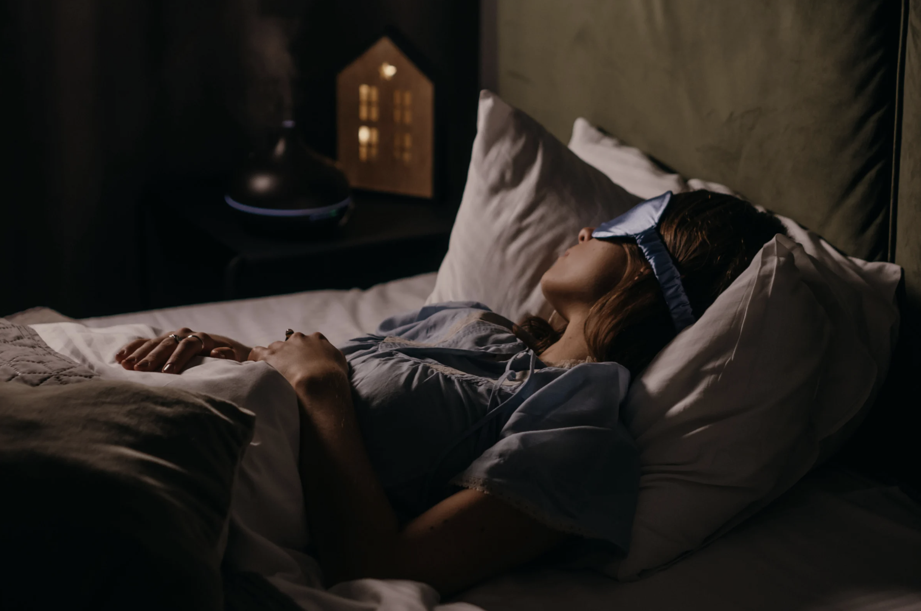Mulher a dormir profundamente em quarto escuro, representando sono reparador e equilíbrio hormonal