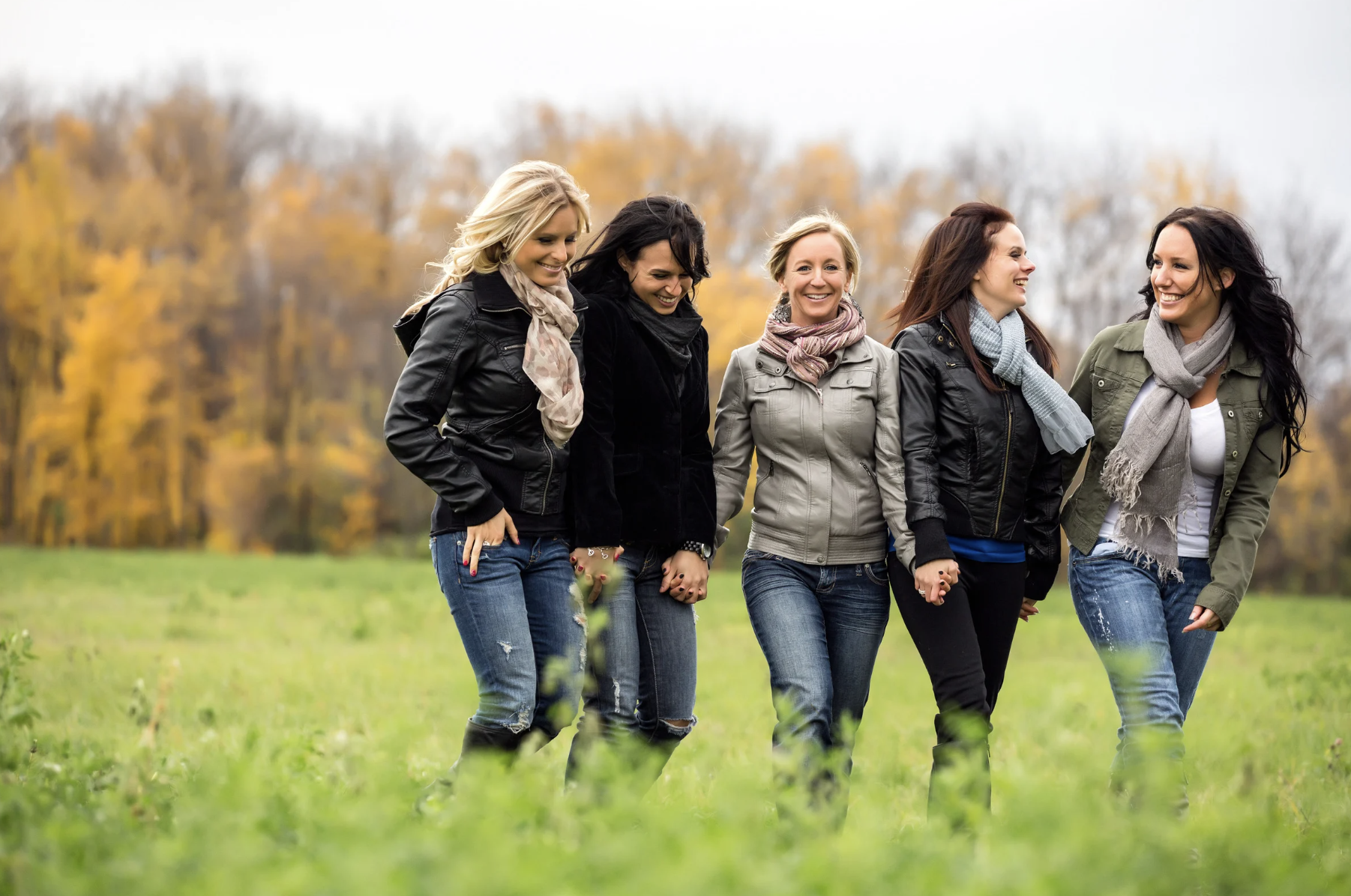 Cinco mulheres felizes a caminhar ao ar livre juntas.